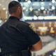 Armed security guard keeps order in store, police officer stands in modern mall